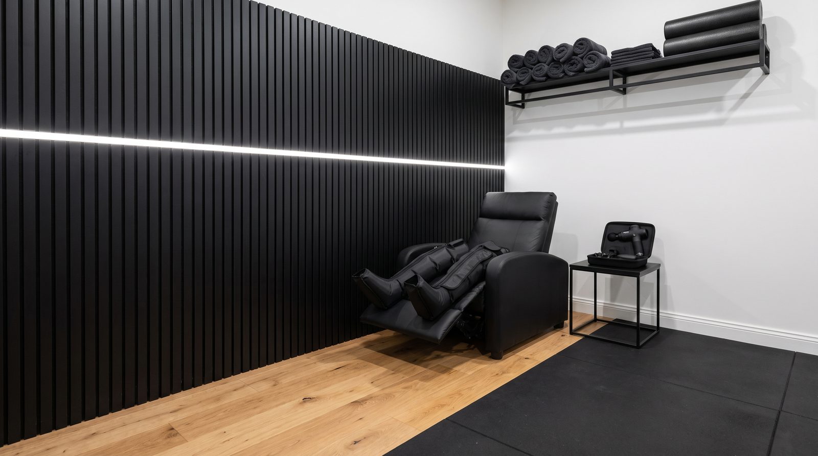 Rincón de recovery con sillón reclinable, botas de compresión y pistola de masaje